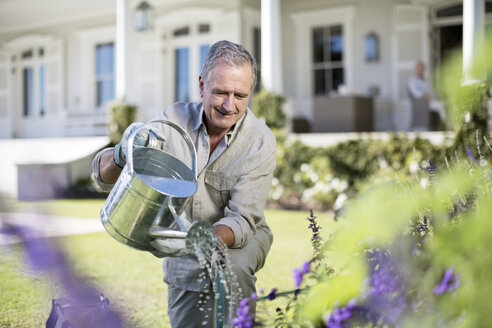 Senior man watering plants in garden - CAIF18596