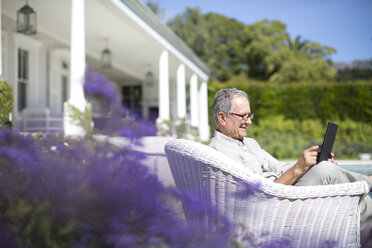 Älterer Mann benutzt digitales Tablet im Garten - CAIF18597