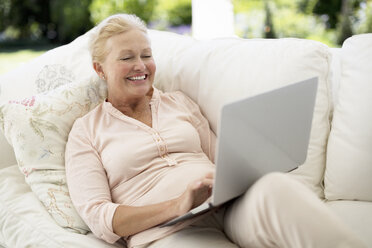 Ältere Frau mit Laptop auf dem Sofa - CAIF18602