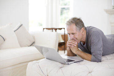 Älterer Mann benutzt Laptop im Wohnzimmer - CAIF18606