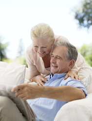Älteres Paar liest Zeitung auf dem Sofa im Innenhof - CAIF18607