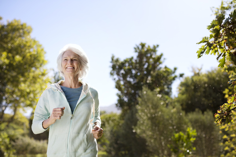 Senior woman running in park stock photo