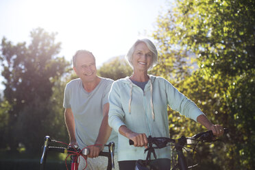 Älteres Paar geht mit Fahrrädern im Park spazieren - CAIF18612