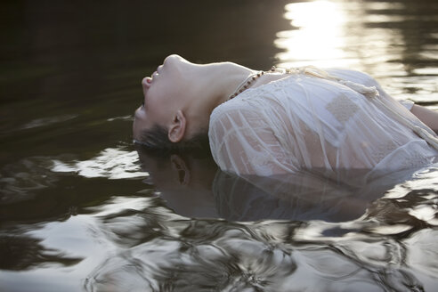 Frau lehnt sich mit dem Kopf im Fluss zurück - CAIF18671