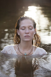 Serene woman with eyes closed in river - CAIF18673