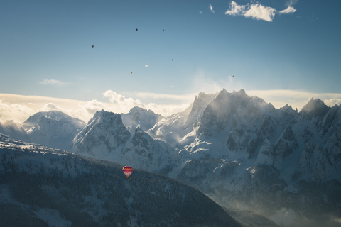Österreich, Salzkammergut, Heißluftballone über Alpenlandschaft mit Gosaukamm im Winter, lizenzfreies Stockfoto