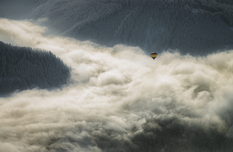 Austria, Salzkammergut, Hot air balloon over clouds in alpine landscape stock photo