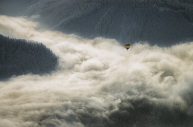 Austria, Salzkammergut, Hot air balloon over clouds in alpine landscape - STCF00411