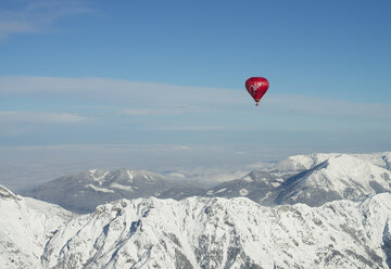 Austria, Salzkammergut, Hot air balloon over alpine landscape in winter - STCF00414