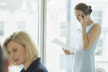 Geschäftsfrau, die im Büro mit einem Handy telefoniert - CAIF18704