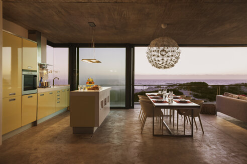 Modern kitchen and dining room overlooking ocean at sunset - CAIF18780