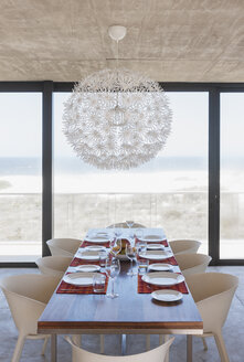 Set table in modern dining room overlooking ocean - CAIF18800