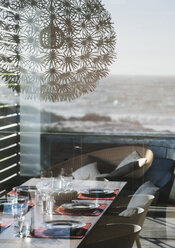 Set table in modern dining room overlooking ocean - CAIF18809