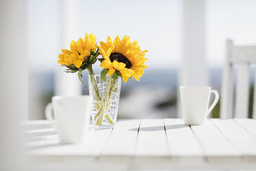 Vase mit Blumen und Kaffeetassen auf dem Küchentisch - CAIF18861
