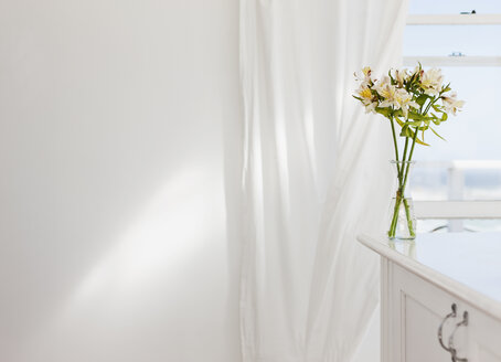 Vase mit Blumen auf dem Schreibtisch in einem weißen Raum - CAIF18873