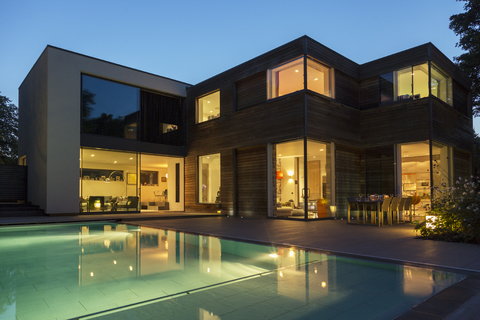 Modernes Haus und Schwimmbad in der Abenddämmerung beleuchtet, lizenzfreies Stockfoto