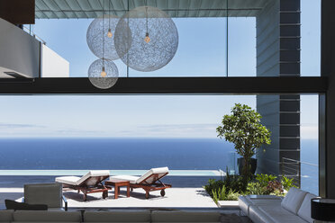 Lounge chairs on balcony overlooking ocean - CAIF18984