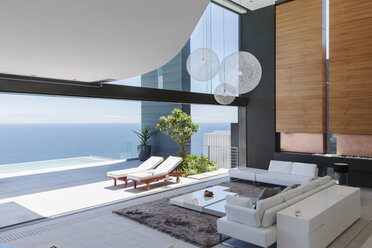 Living room and patio of modern house overlooking ocean - CAIF19001