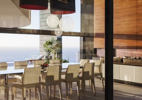 Table and chairs in modern dining room overlooking ocean - CAIF19008