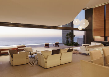 Living room in modern house overlooking ocean at sunset - CAIF19015