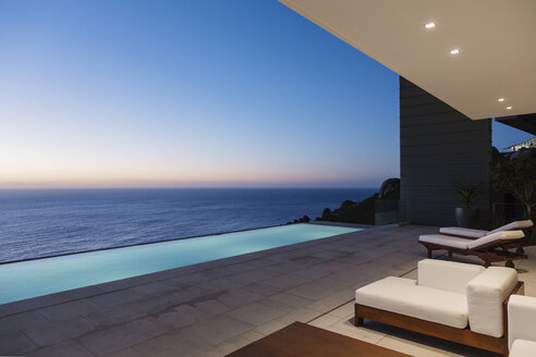 Moderne Terrasse und Infinity-Pool mit Blick auf das Meer bei Sonnenuntergang - CAIF19019