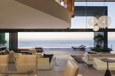 Modern living room overlooking ocean at sunset - CAIF19032