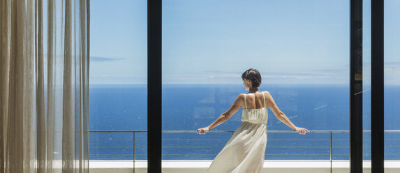 Frau schaut vom Balkon aufs Meer - CAIF19056