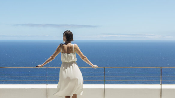Frau schaut vom Balkon aufs Meer - CAIF19059