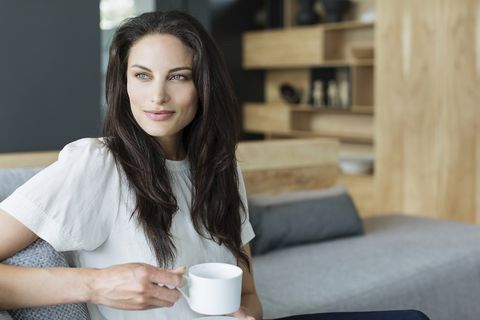 Frau trinkt Kaffee im Wohnzimmer, lizenzfreies Stockfoto