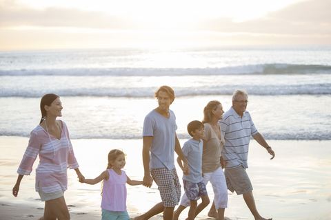 Mehrgenerationen-Familie beim gemeinsamen Spaziergang am Strand, lizenzfreies Stockfoto