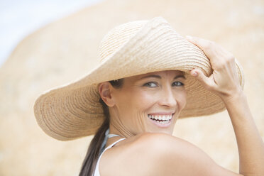 Woman wearing straw hat on beach - CAIF19137