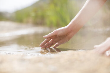 Frau taucht Finger in ländlichen Teich - CAIF19148