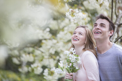 Lächelndes Paar unter einem Baum mit weißen Blüten - CAIF19190