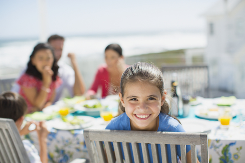 Lächelndes Mädchen am Tisch auf der sonnigen Veranda, lizenzfreies Stockfoto