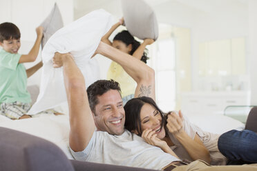 Family enjoying pillow fight in living room - CAIF19319