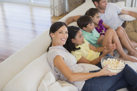 Familie schaut einen Film auf dem Sofa im Wohnzimmer, lizenzfreies Stockfoto