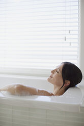 Woman relaxing in bubble bath - CAIF19345