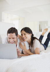 Couple using laptop on bed - CAIF19360