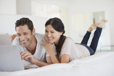 Couple using laptop on bed - CAIF19371