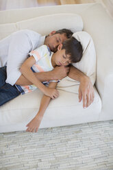 Vater und Sohn machen ein Nickerchen auf dem Sofa im Wohnzimmer - CAIF19378