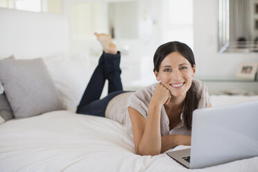 Frau mit Laptop auf dem Bett - CAIF19380