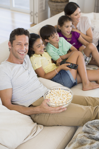 Familie beim Fernsehen auf dem Sofa im Wohnzimmer, lizenzfreies Stockfoto