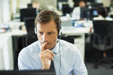 Businessman wearing headset in office - CAIF19395