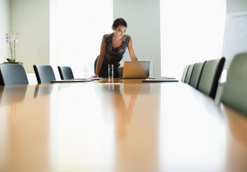 Businesswoman using laptop at conference table - CAIF19396