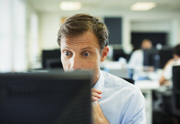 Überrumpelter Geschäftsmann am Computer im Büro - CAIF19403