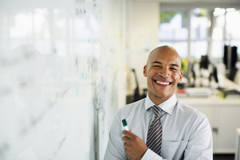 Geschäftsmann lächelnd am Whiteboard im Büro, lizenzfreies Stockfoto