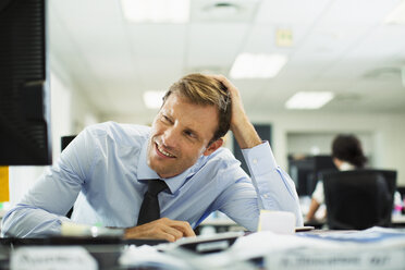 Businessman squinting at desk in office - CAIF19420