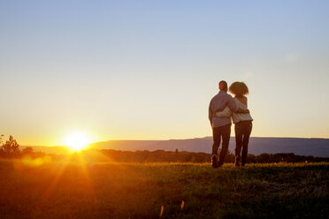 Rückansicht eines im Gras stehenden Paares gegen den klaren Himmel bei Sonnenuntergang - CAVF09563
