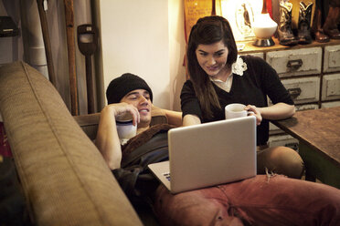 Paar, das einen Laptop benutzt, während es sich in einem Café entspannt - CAVF09572