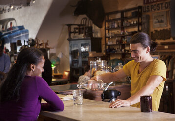 Männlicher Besitzer schenkt einem Kunden in einem Café ein Getränk ein - CAVF09589